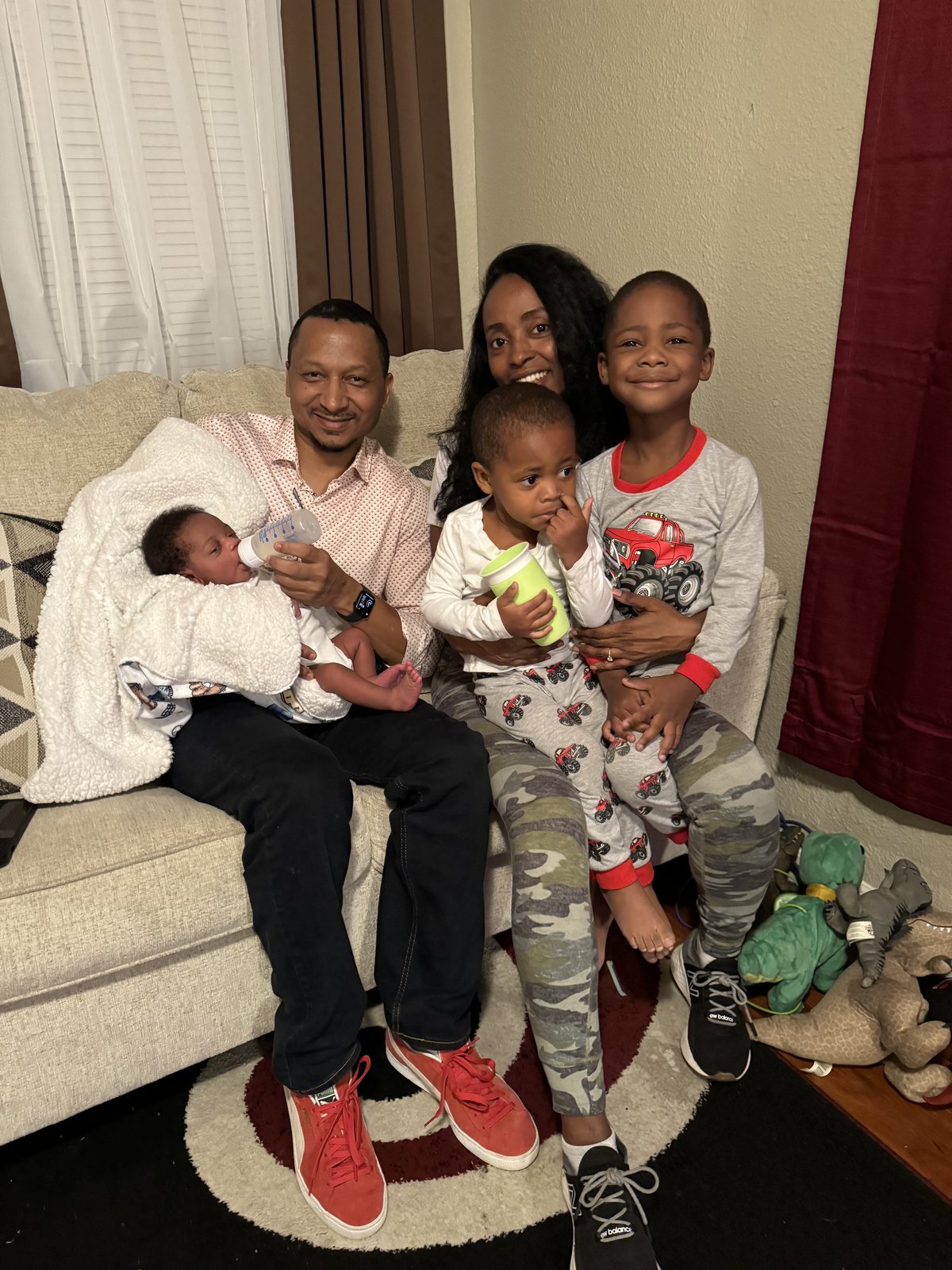 Herman and Rontunya on the couch with the kids, feeding a baby